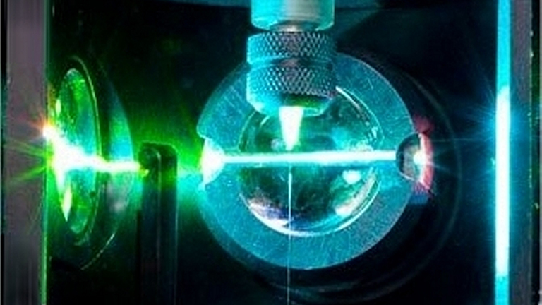 Green laser hitting a metal sphere